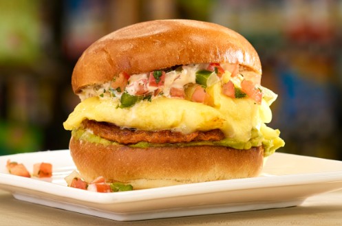Cheeseburger with melted cheese, lettuce, and tomato on a toasted bun on a white plate.